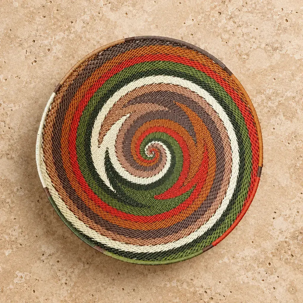 Handwoven african zulu wire bowl with vibrant spiral pattern in earthy tones made from recycled telephone wire