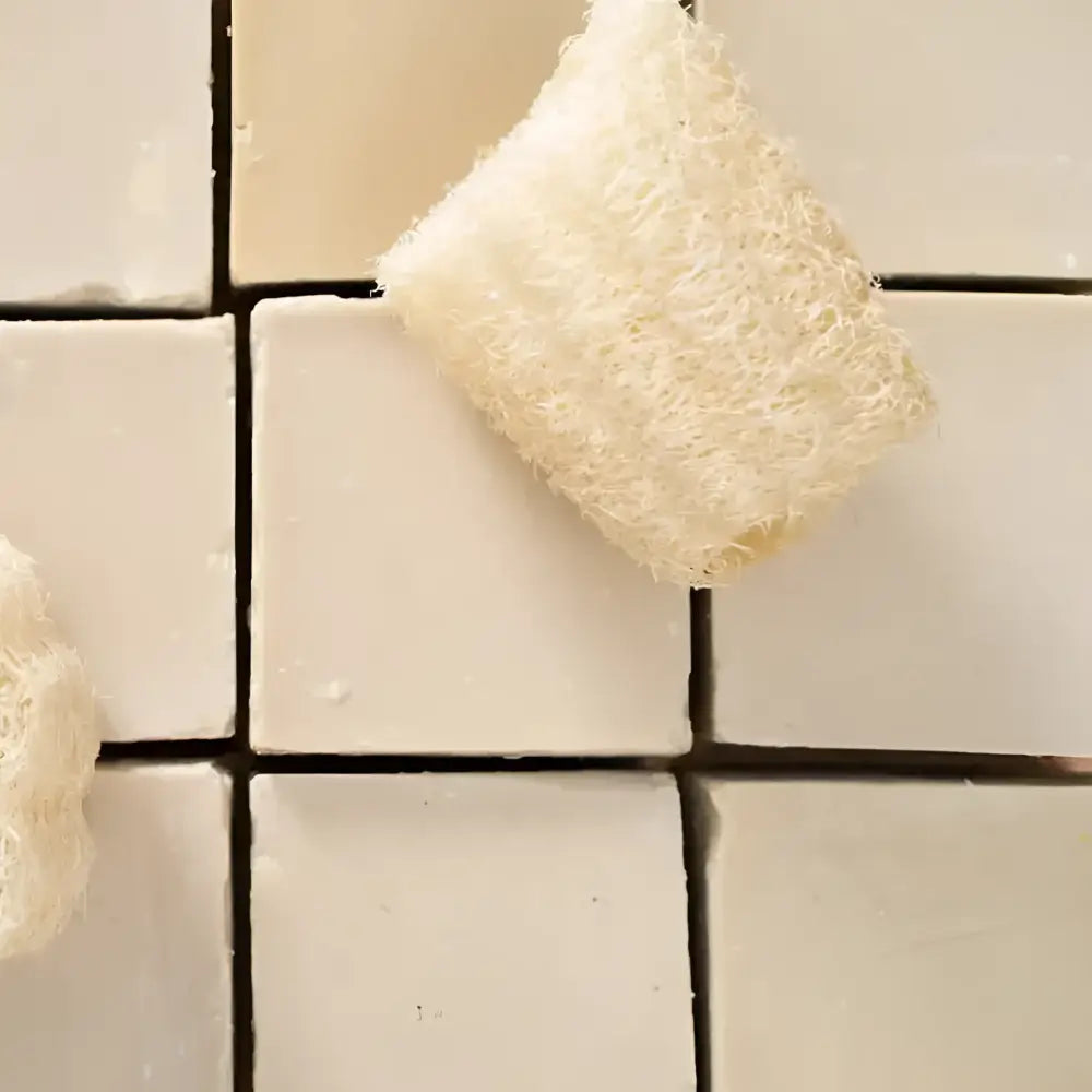 White loofah sponge on tiled surface with Authentic Turkish Black Clay Soap