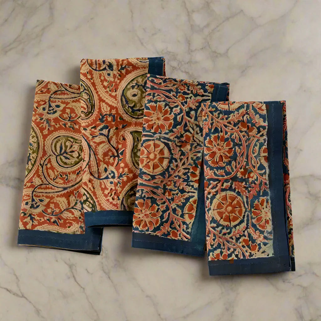 Four folded Block Print Compass Paisley Napkins with floral and paisley patterns and teal borders