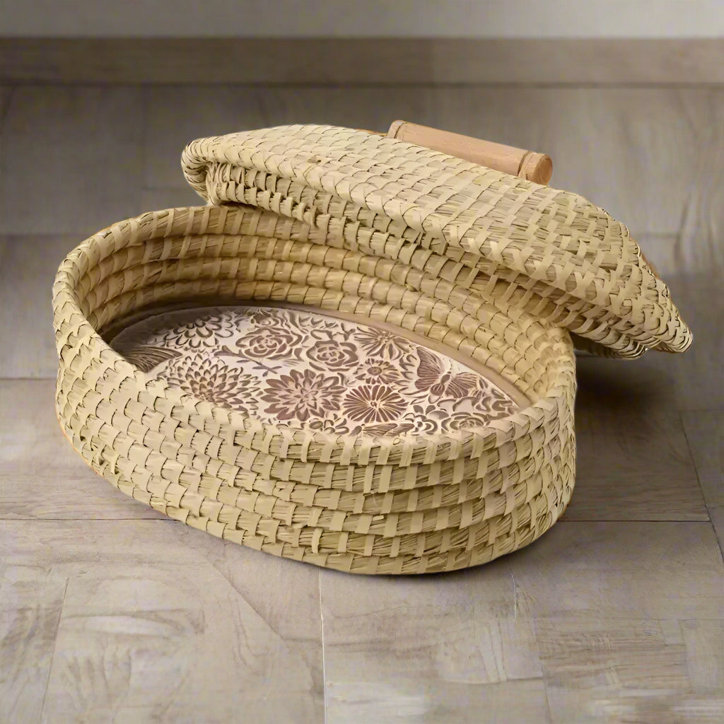 Oval woven straw bread warming basket with floral interior and wooden handle for bread
