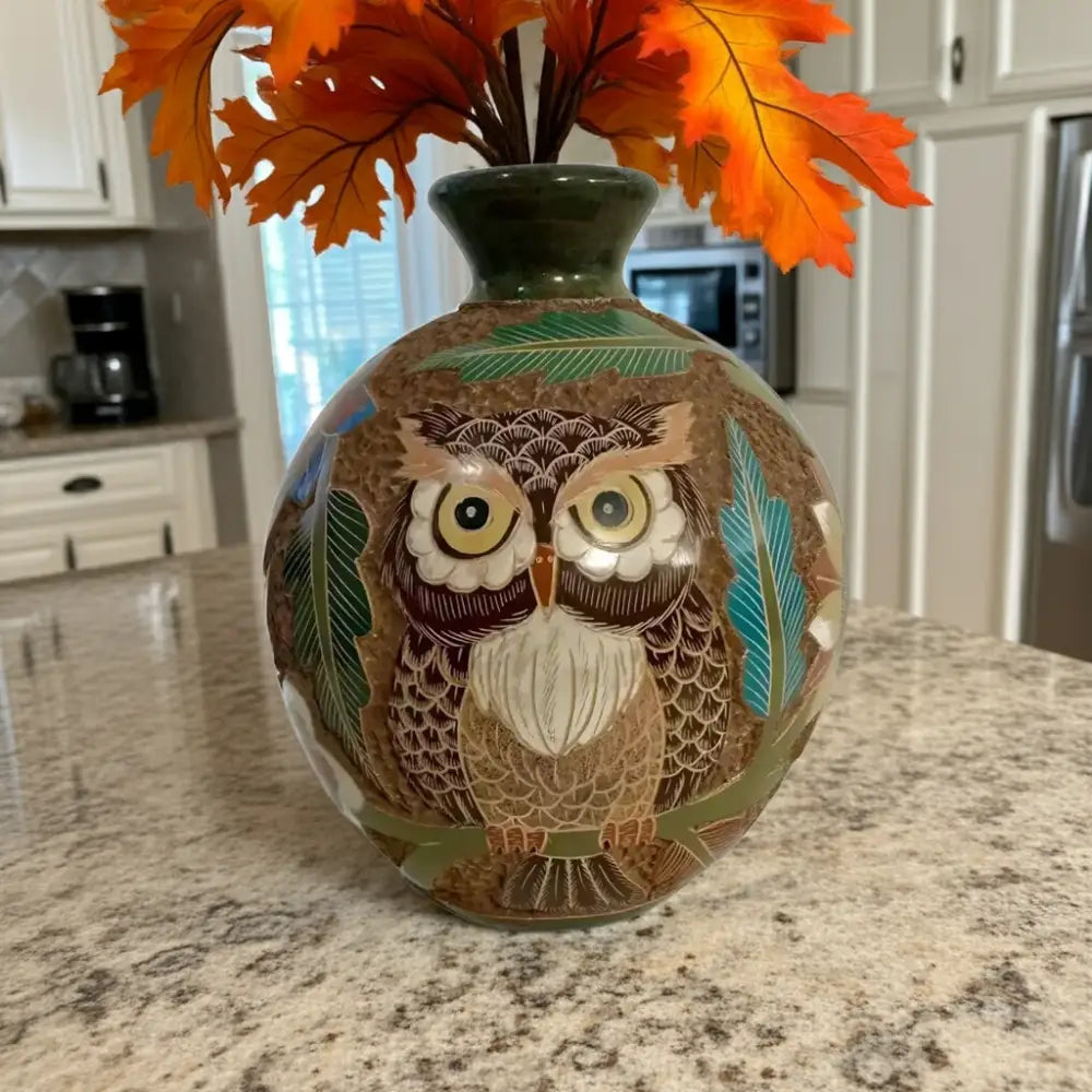 Decorative carved clay owl vase with intricate carvings and autumn leaves display