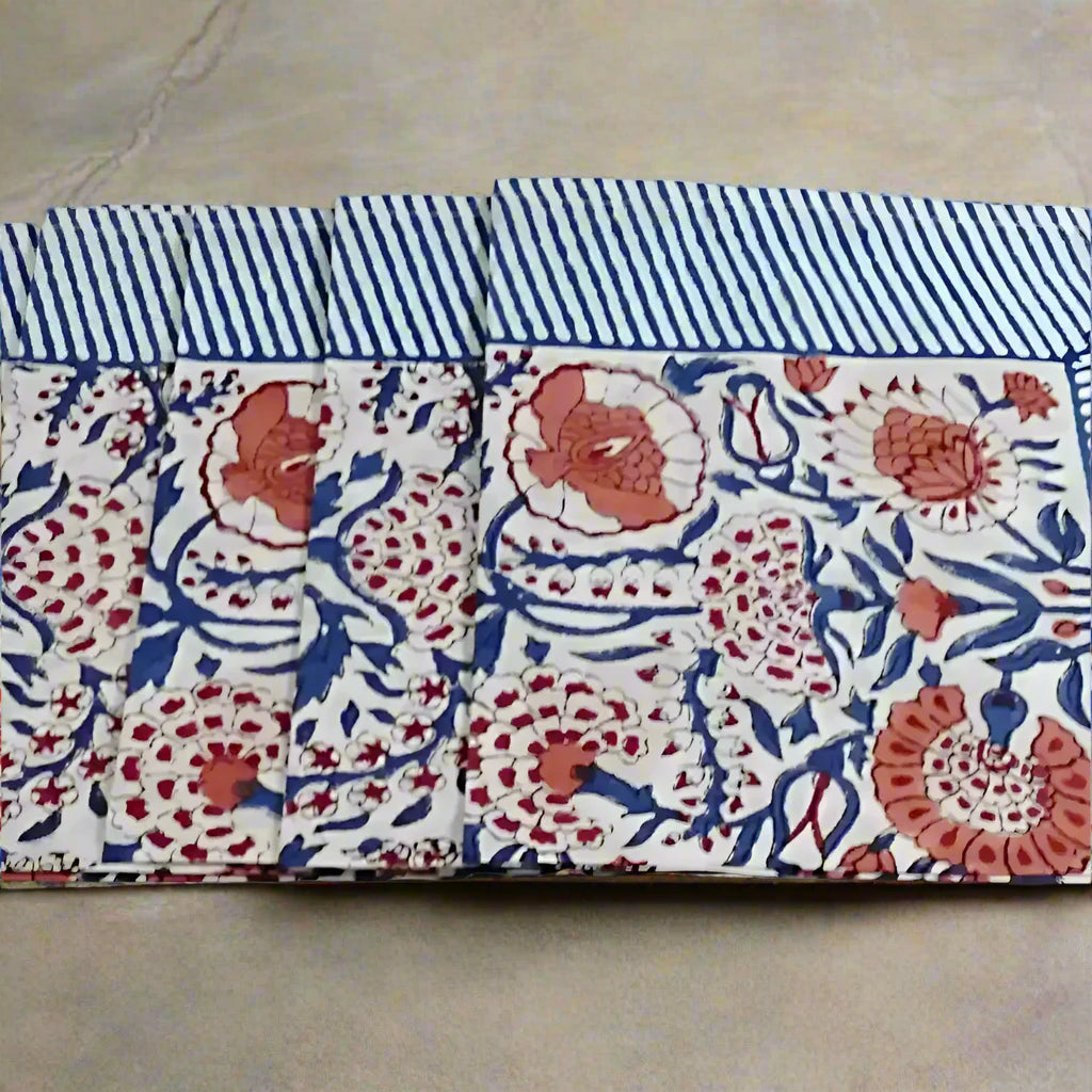 Four folded Green Heron hand block print napkins with blue stripes and coral florals