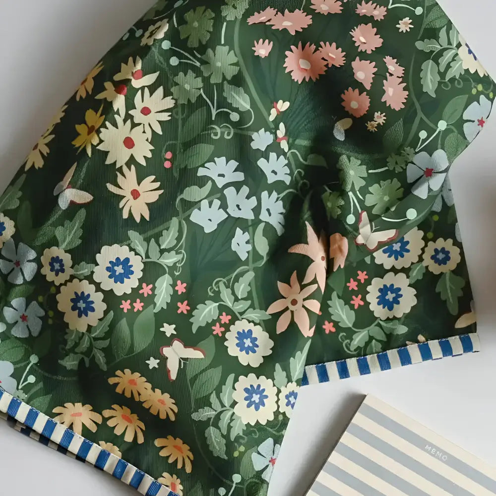 A dark green cotton tea towel with vibrant pink white and blue floral pattern perfect for kitchen use