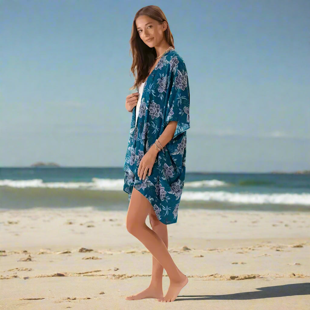 Young woman in teal floral kimono cover up on the beach for a stylish look