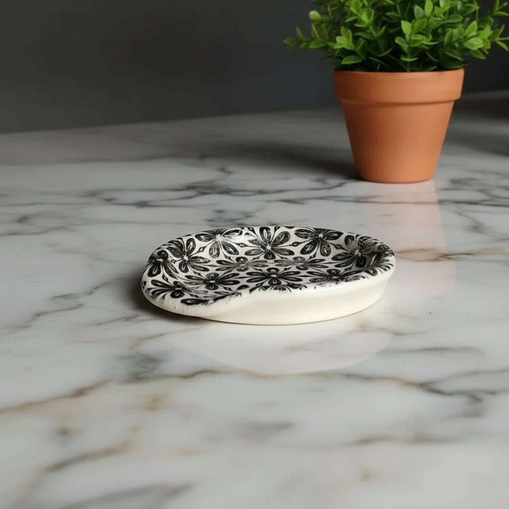 White ceramic spoon rest with black floral pattern for kitchen counter use