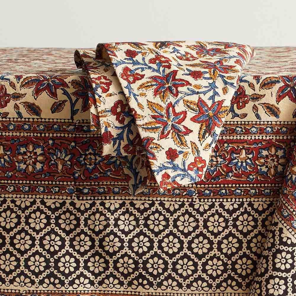 Rust and black multicolor printed tablecloth on table with a napkin.