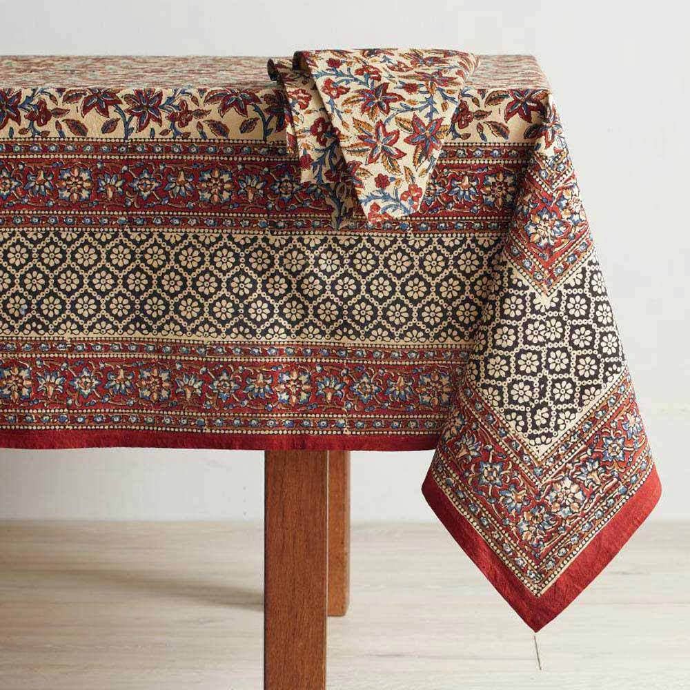 Rust and black multicolor printed tablecloth on table with a napkin.
