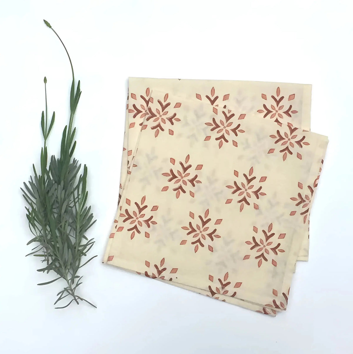 Folded cream-colored organic cotton napkin with hand block printed snowflake pattern