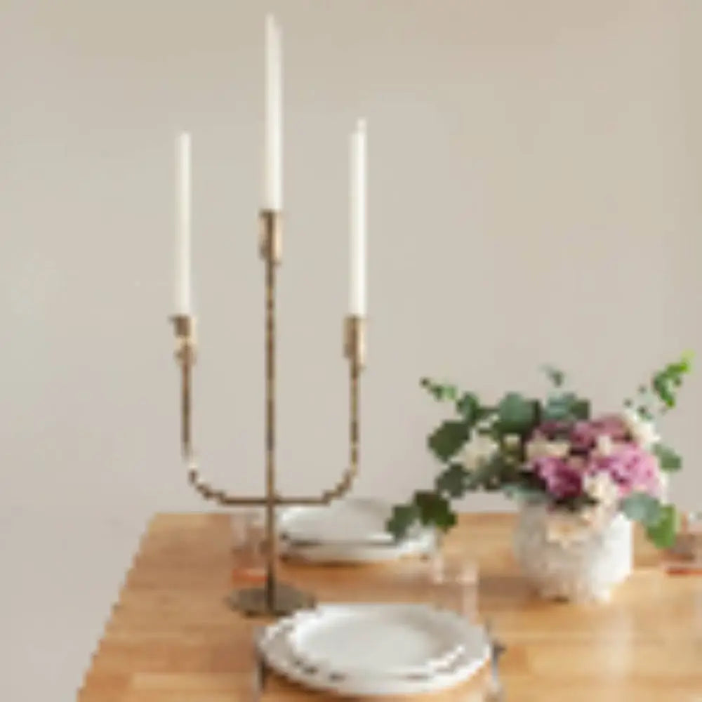 Hand Forged Iron Candelabra in brass finish on a wooden table with a place setting