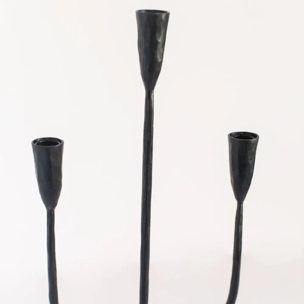 Three sleek black metal candle holders from a hand-forged iron candelabra with a premium feel