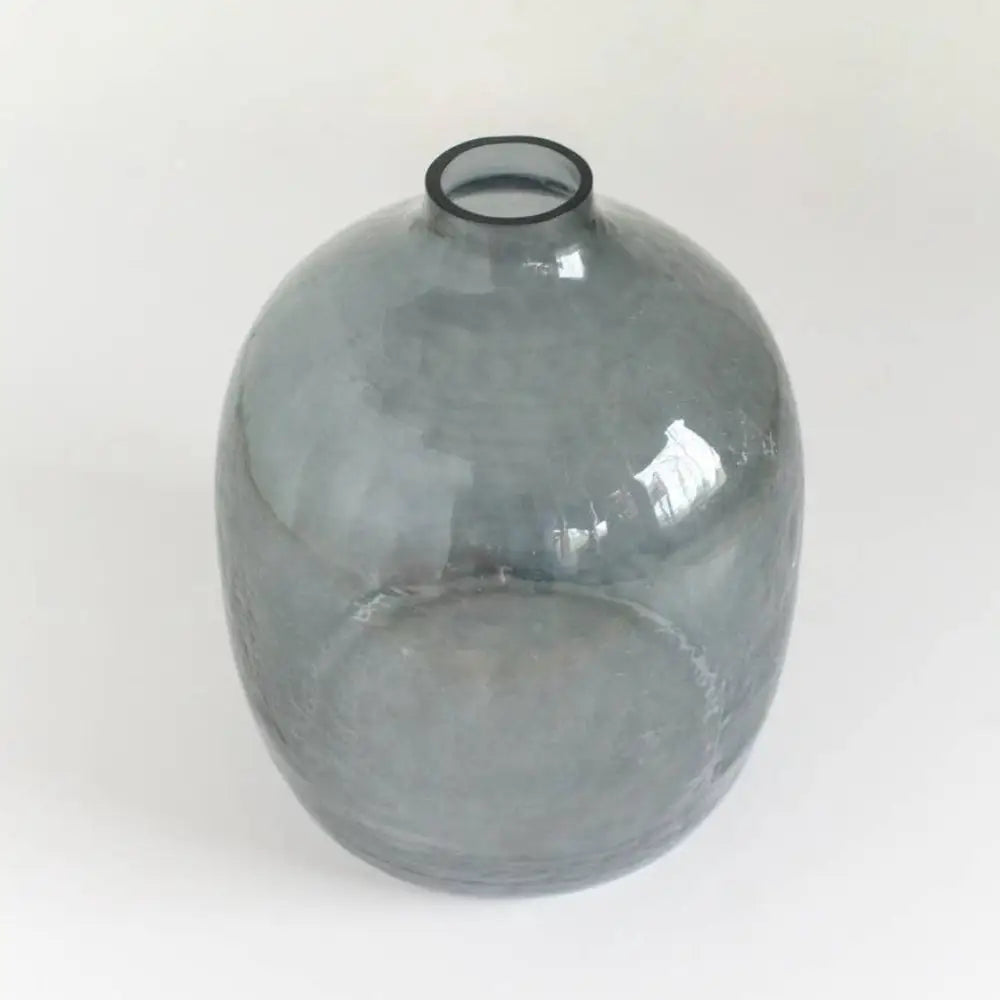 Handblown hammered glass vase in blue gray on light background.