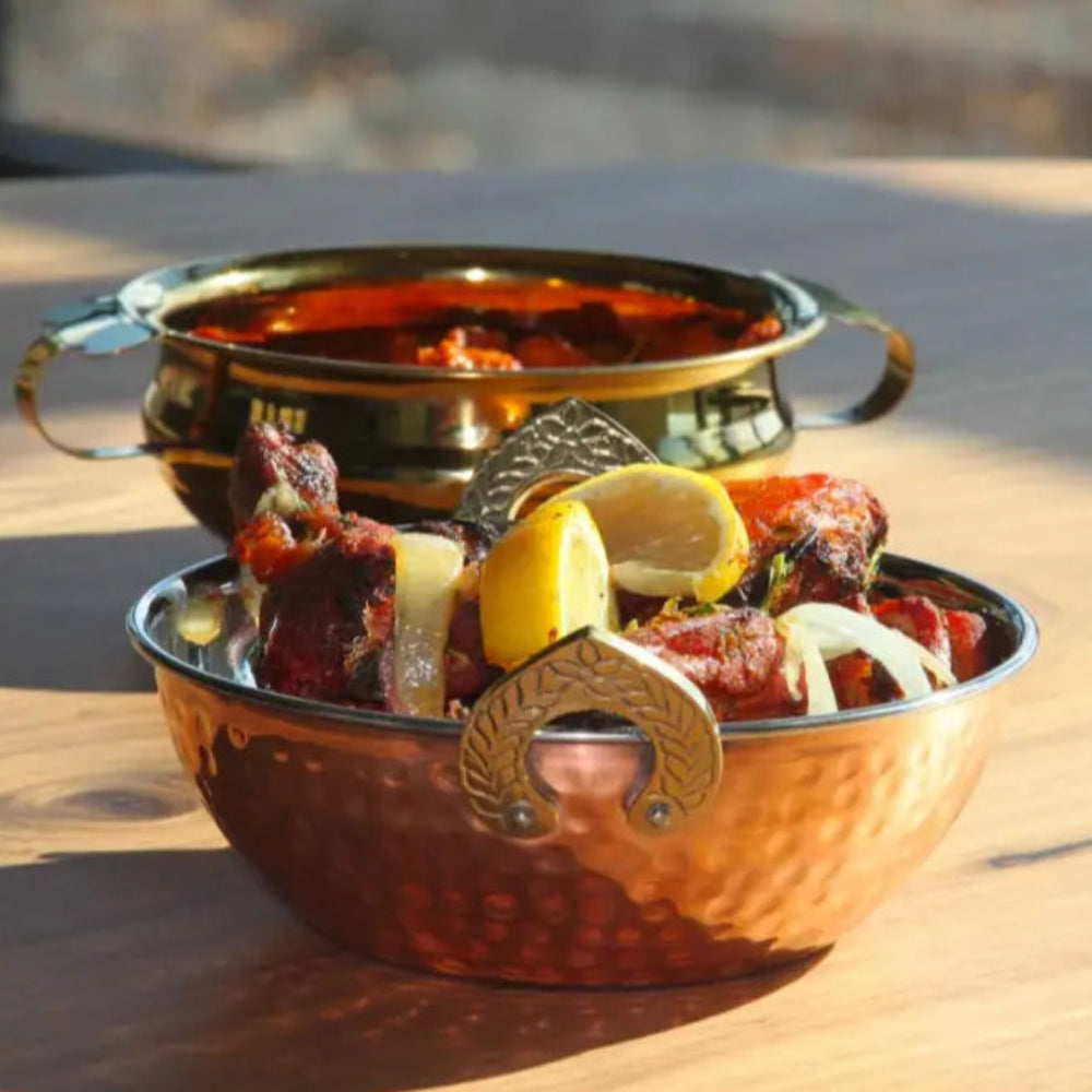 Two copper handi double wall serving bowls filled with Indian cuisine for stylish serving