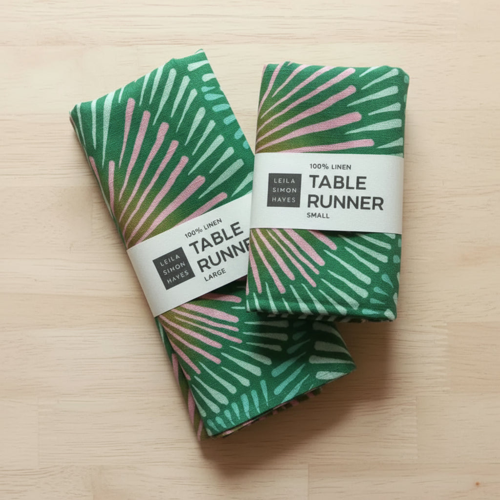 Two folded handmade eco-friendly green and pink patterned linen table runners
