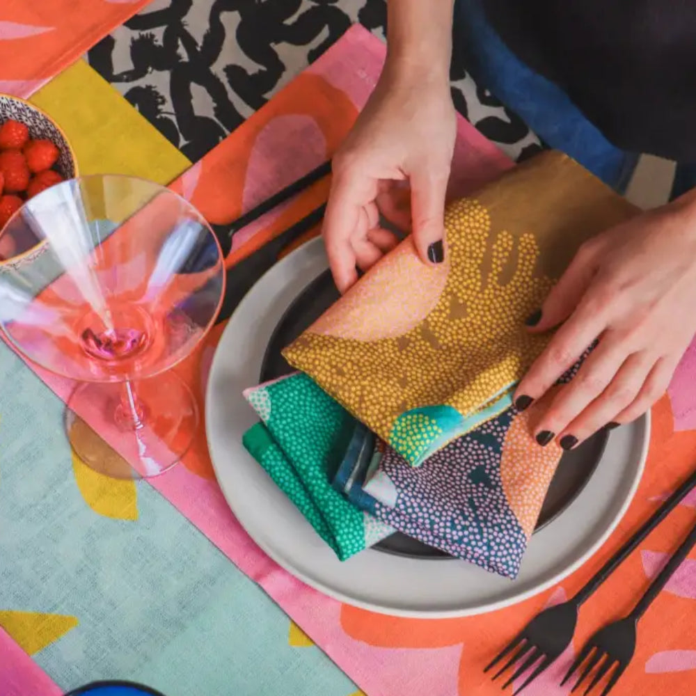 Colorful handcrafted eco-friendly linen napkins set in blue green coral yellow on a plate