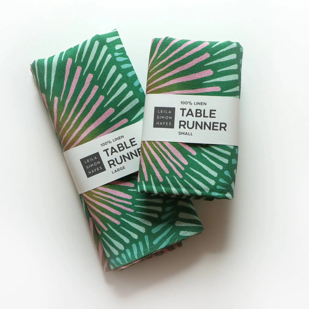 Folded green and pink patterned handmade european linen table runner with burst pattern in packaged form
