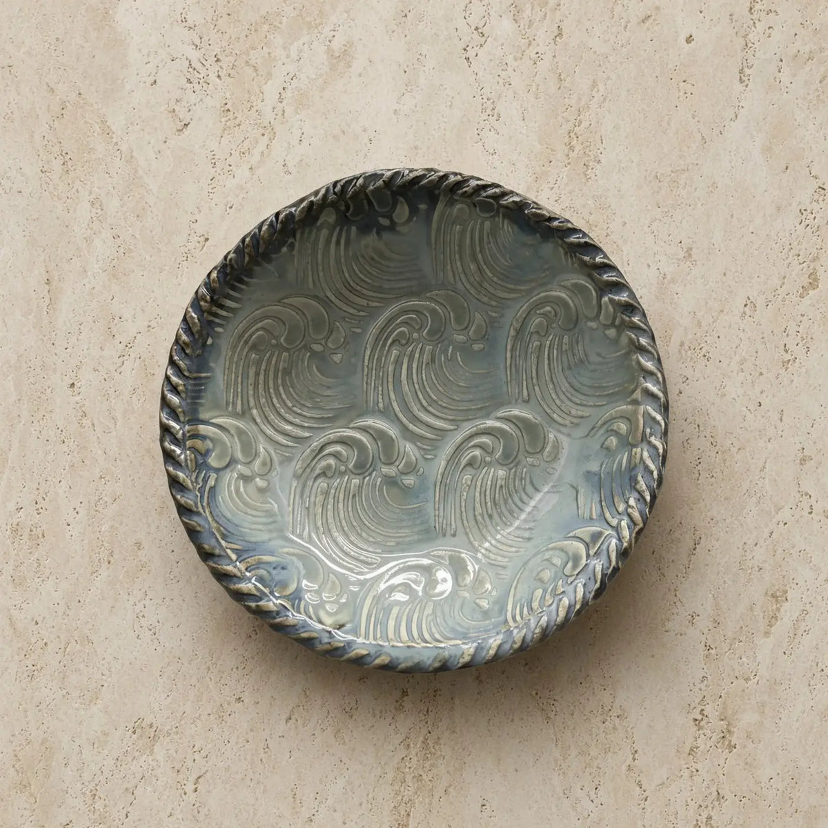 Handmade pottery ring dish in seafoam and blue with gray glaze, raised wave patterns, and twisted rope rim