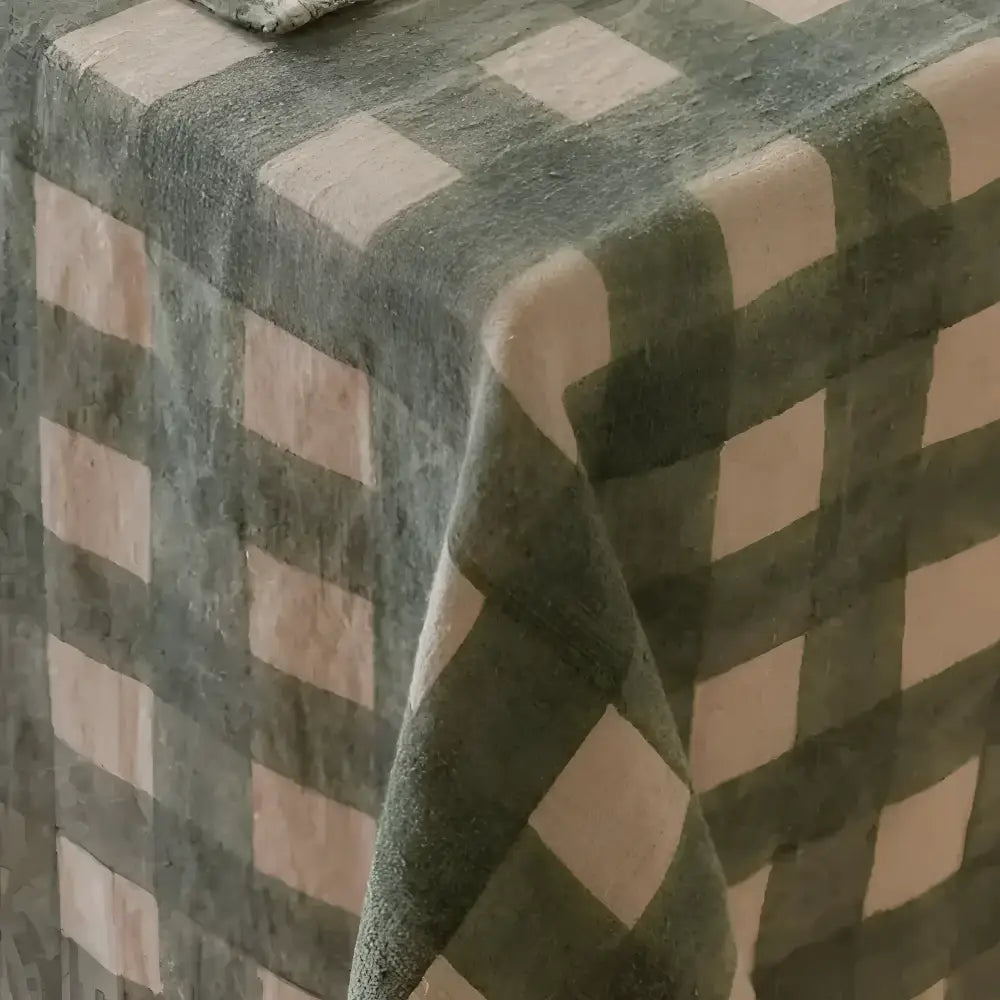 Fabric covering on edge of wood table with green checkered pattern.