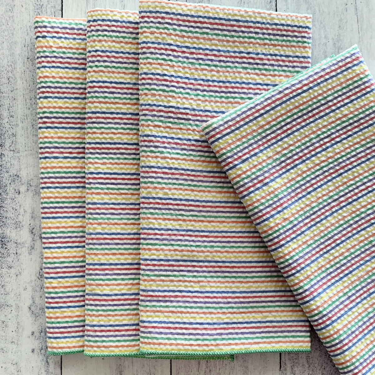 Set of four colorful rainbow seersucker cloth napkins with red green blue and yellow stripes in waffle weave texture