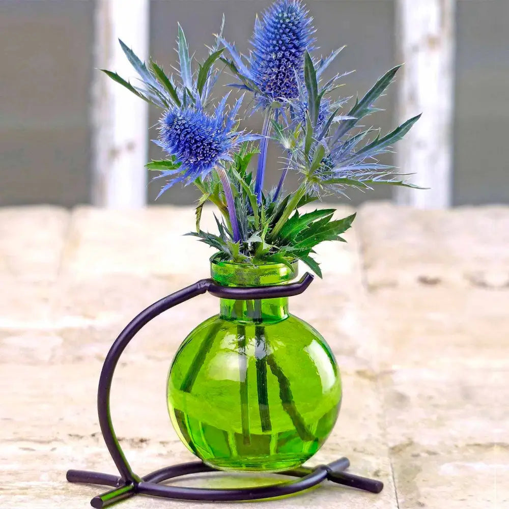 Vibrant blue thistle flowers in a recycled glass mini vase with black metal stand