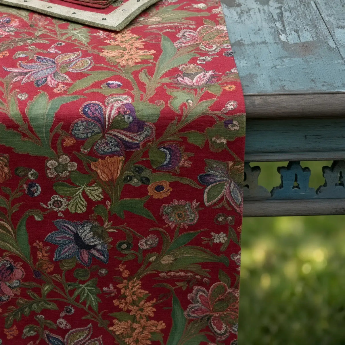 A handmade red floral table runner with intricate green purple and gold floral patterns perfect for any table