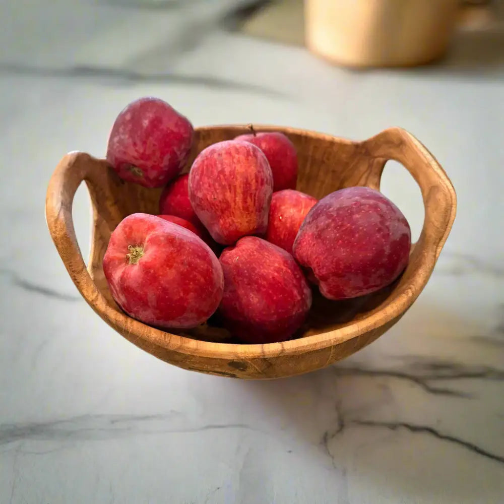 Rustic teak bowl with handles filled with fresh red apples for a cozy vibe
