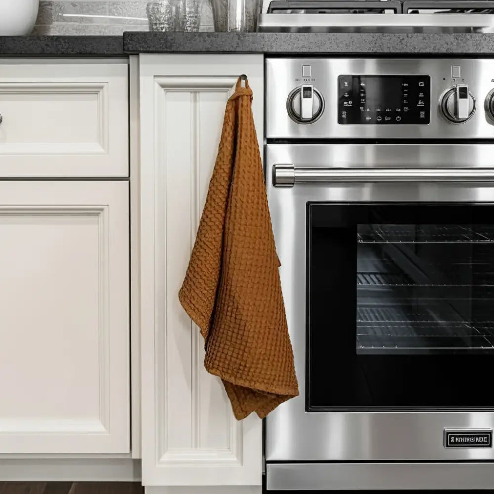 Stainless steel electric oven with black glass door on linen-cotton blend waffle kitchen towel