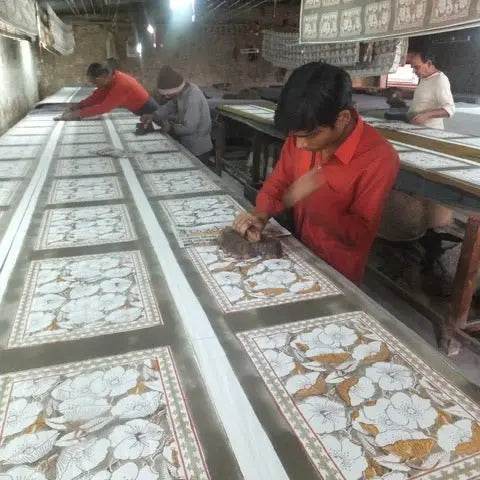 Workers hand-printing floral patterns on fabric using wooden blocks in textile art with natural dyes for fabric
