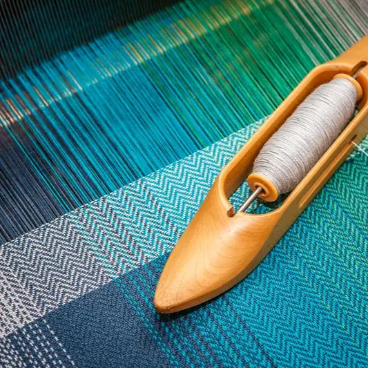 Wooden weaving shuttle with gray yarn bobbin for traditional shuttle loom weaving