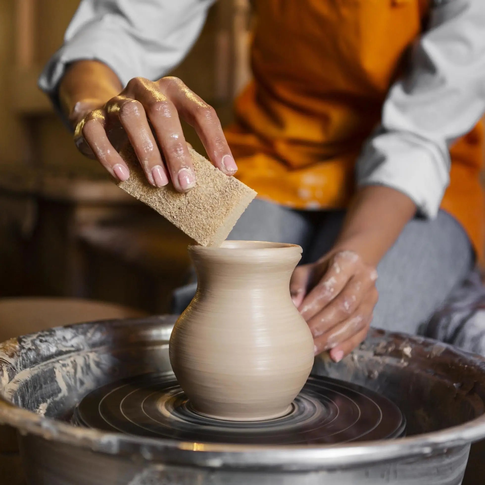 Potter’s hands shaping a clay vase on a spinning wheel in American Artisan Collection