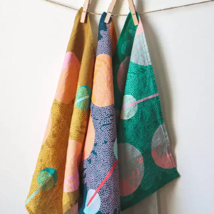 Mustard yellow and green patterned tea towels with wooden pegs