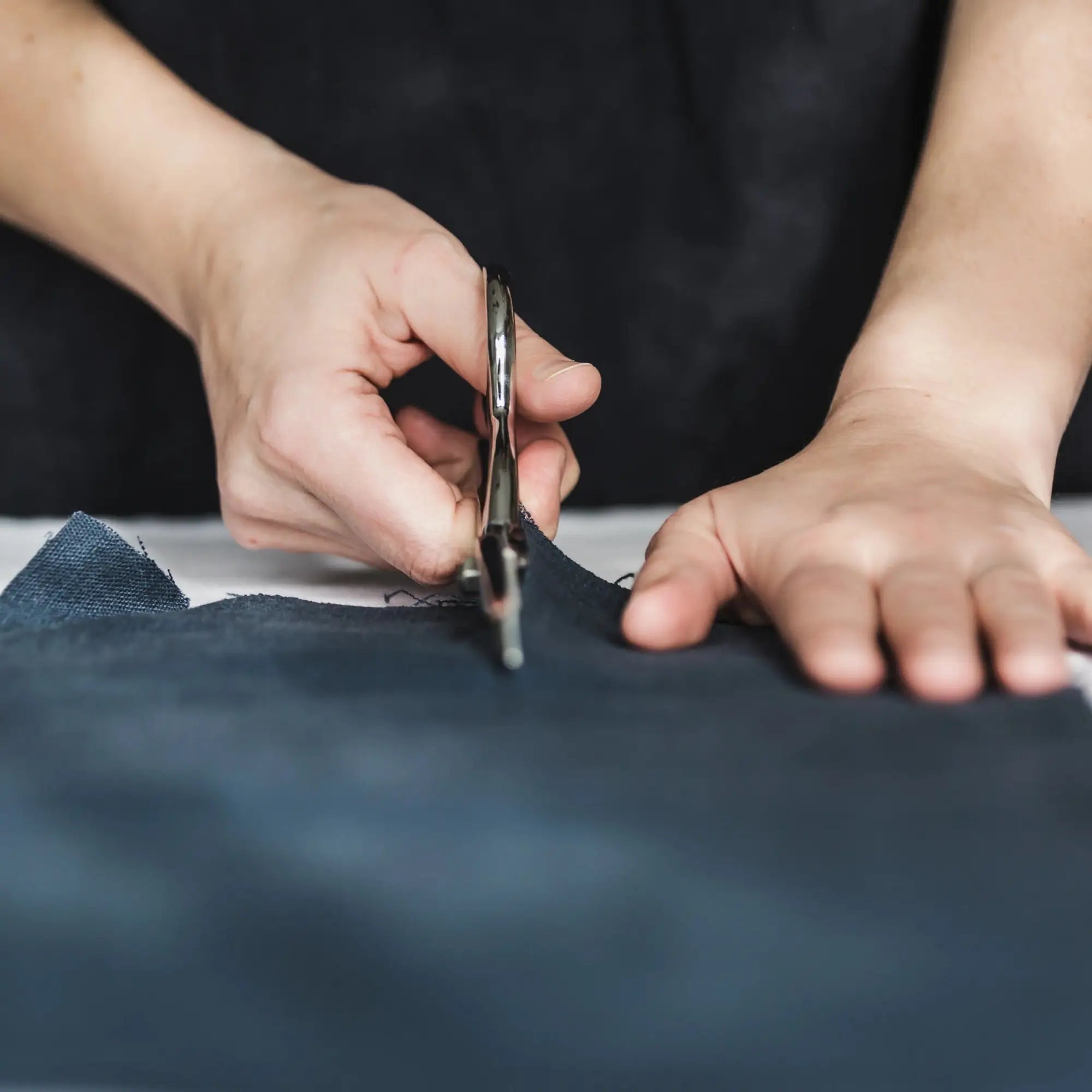 Metal scissors cutting dark blue fabric from European Artisan Collection