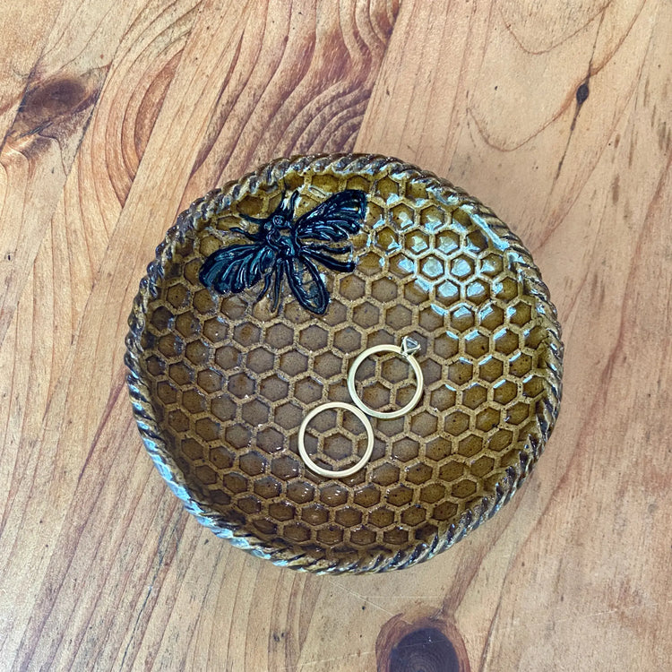 Ceramic honeycomb pattern trinket dish with bee embellishment holding gold rings in Handcrafted Rustic Pottery Collection