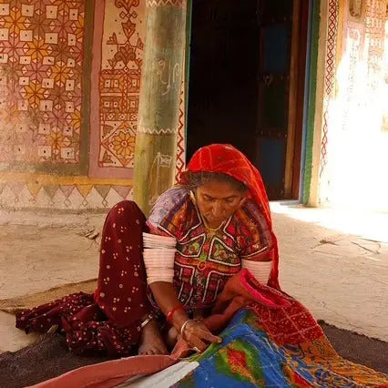 Elderly woman from Indian Artisan Collection handcrafting textiles in traditional attire