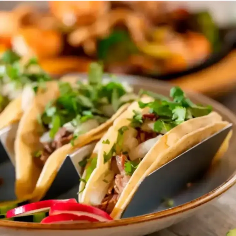 Three beef tacos with lettuce and cilantro on white plate