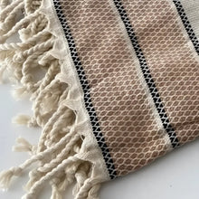 Natural colored linen bath towel with brown stripes and tassels.
