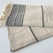 Natural colored linen bath towel with grey stripes and tassels.