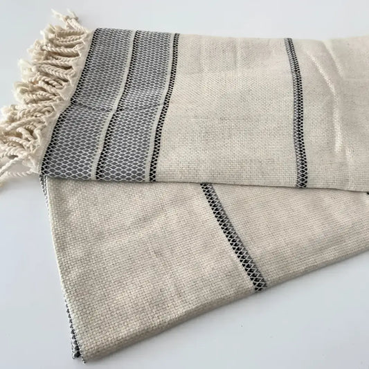 Natural colored linen bath towel with grey stripes and tassels.