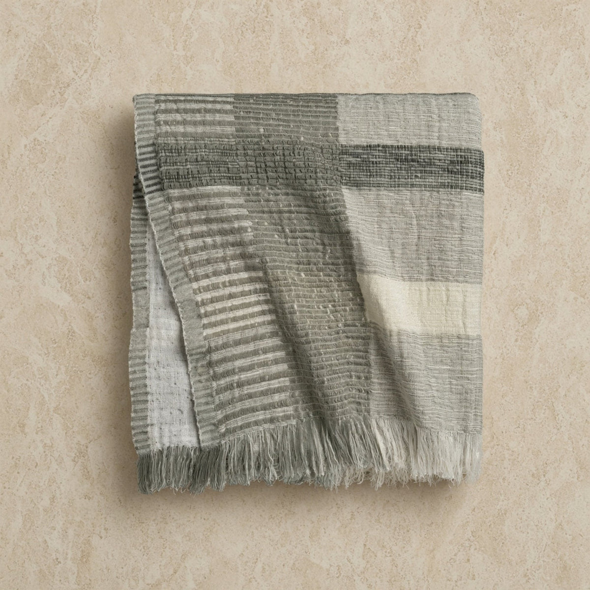 A handloomed abstract oversized throw blanket in muted gray and off-white stripes with fringed edges and imperfect pattern