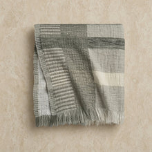 A handloomed abstract oversized throw blanket in muted gray and off-white stripes with fringed edges and imperfect pattern