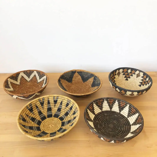 Assorted handmade African baskets in various natural colors with striking geometric designs.