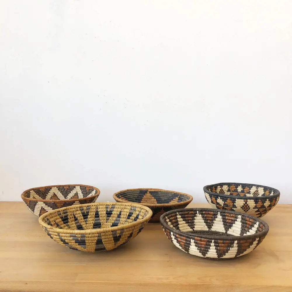 Assorted handmade African baskets in various natural colors with striking geometric designs.