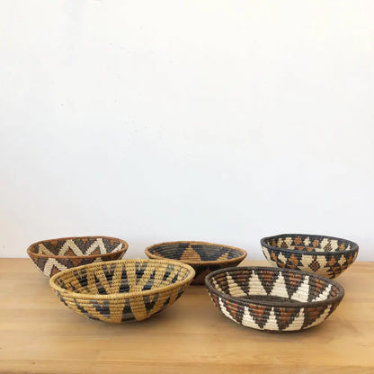 Assorted handmade African baskets in various natural colors with striking geometric designs.