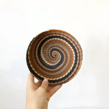 Baskets made of flexible wire that have been handwoven into striking geometric designs in neutral desert color tones.