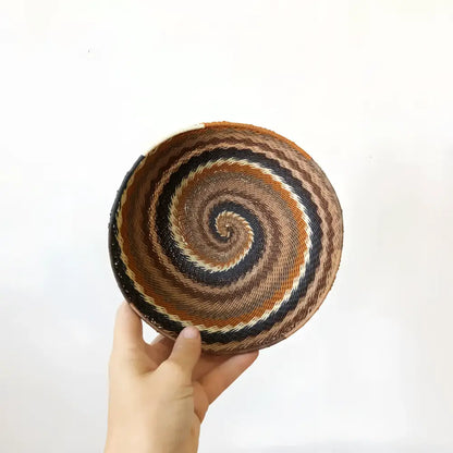 Baskets made of flexible wire that have been handwoven into striking geometric designs in neutral desert color tones.