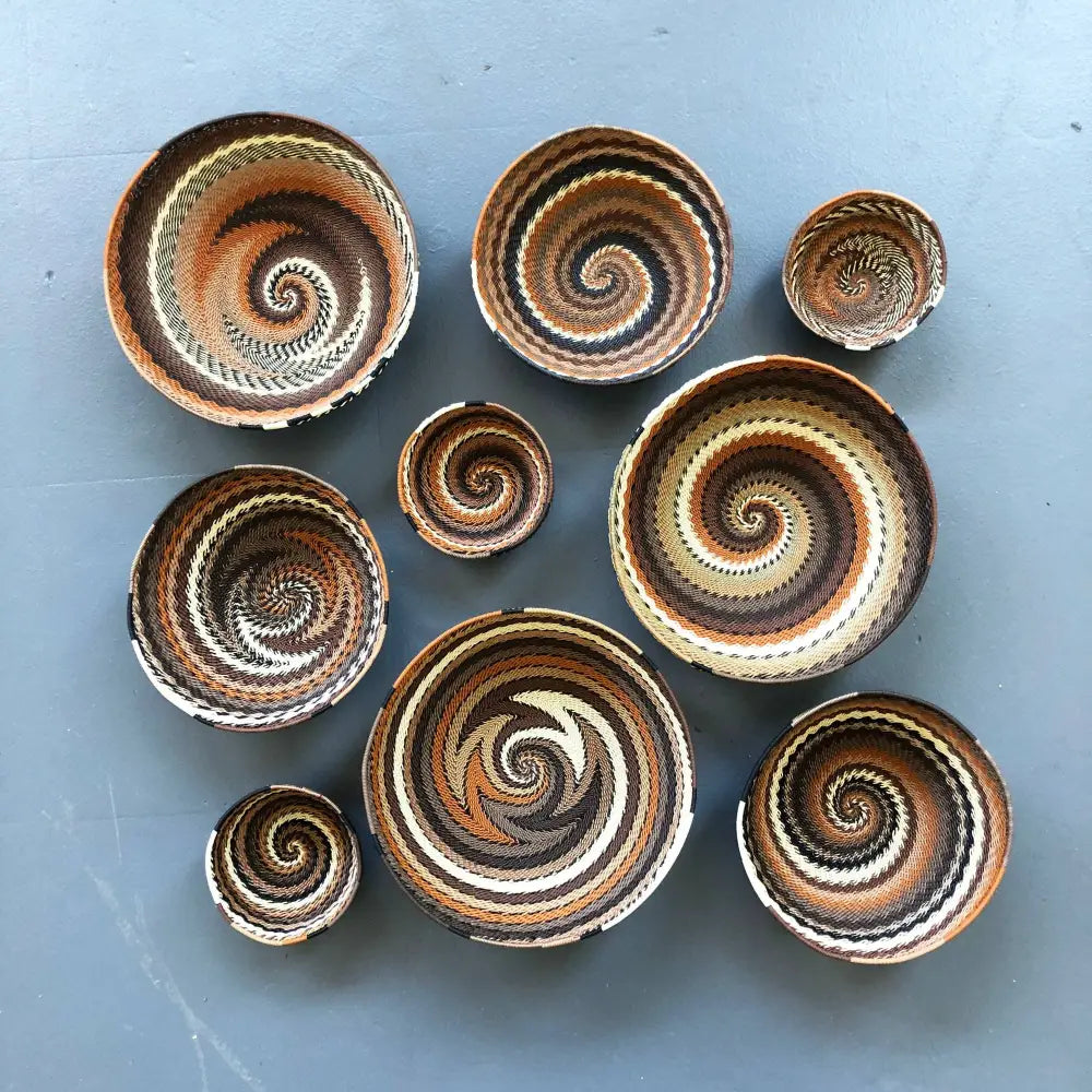 Baskets made of flexible wire that have been handwoven into striking geometric designs in neutral desert color tones.