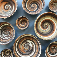 Baskets made of flexible wire that have been handwoven into striking geometric designs in neutral desert color tones.