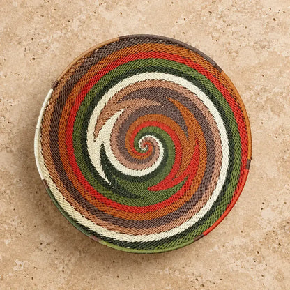 Handwoven african zulu wire bowl with vibrant spiral pattern in earthy tones made from recycled telephone wire