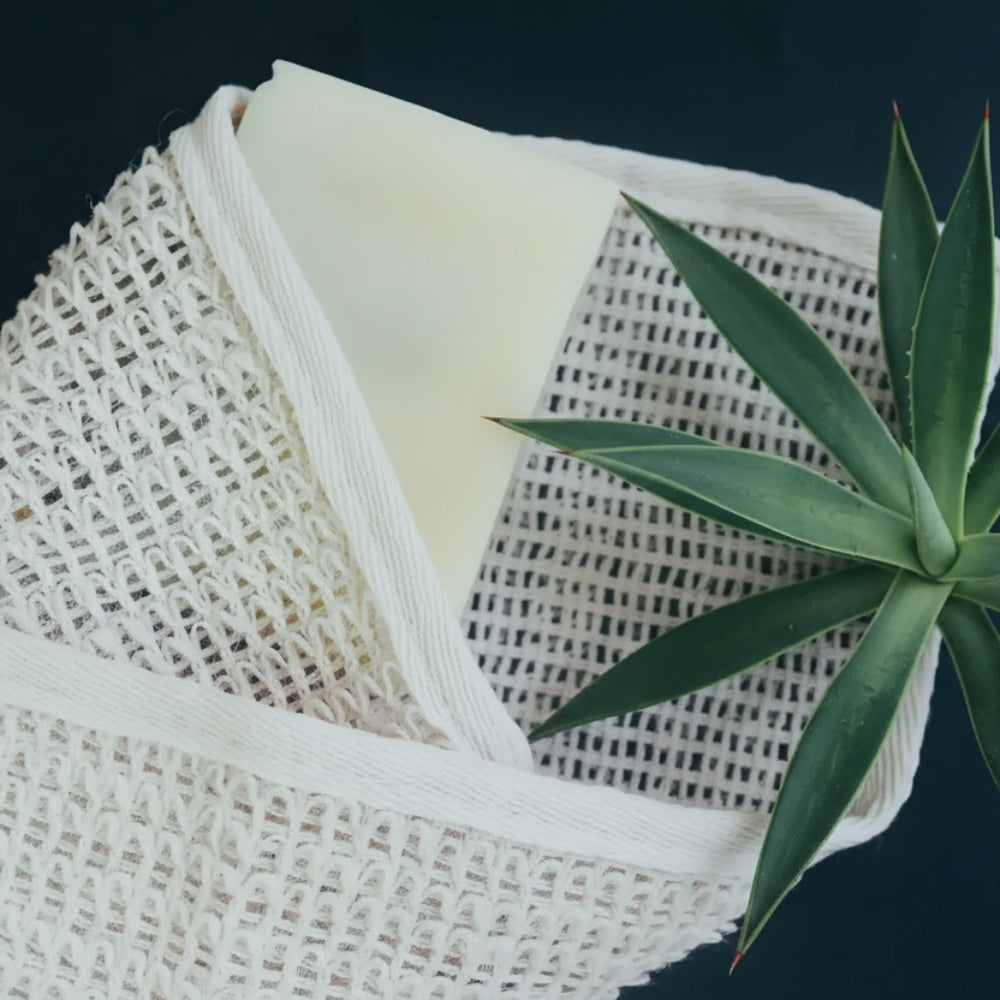 Eco-friendly handmade Agave Wash Cloth with coarse texture holding yellow soap and rosemary