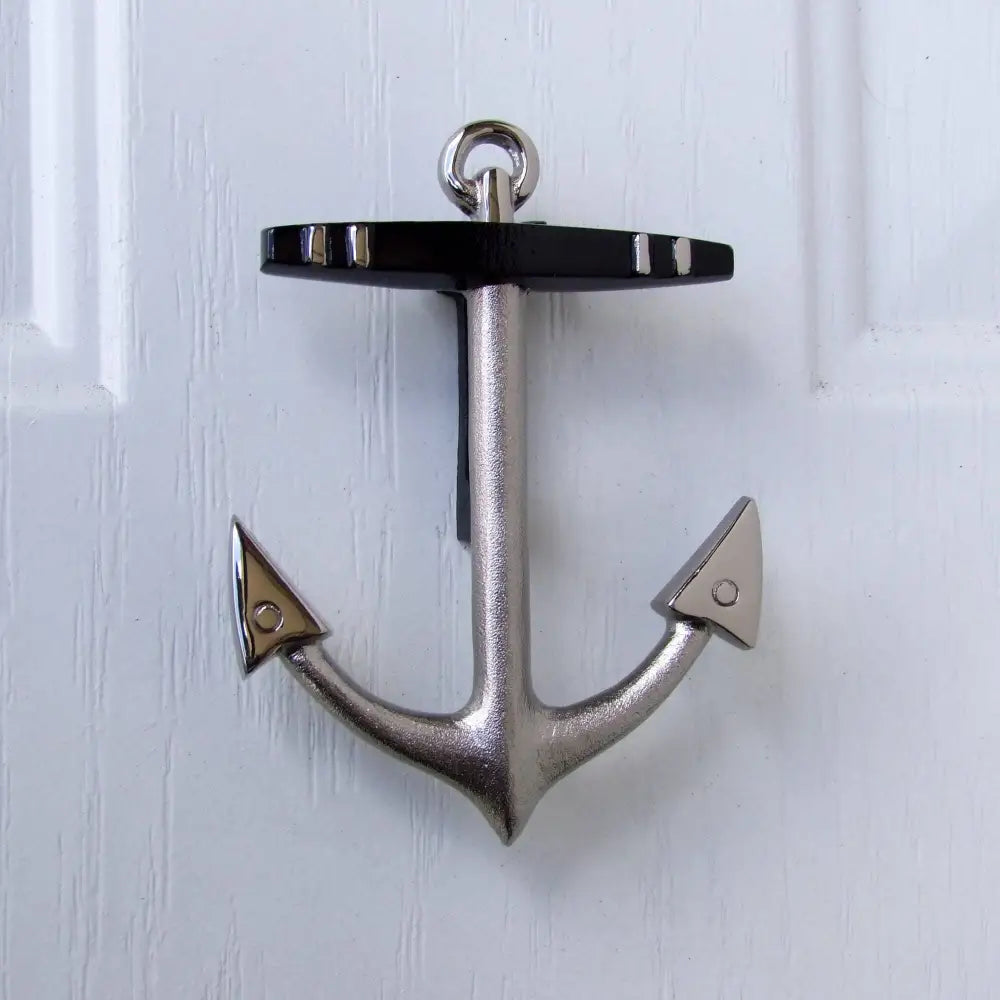 Metallic anchor-shaped door knocker on a white wooden door