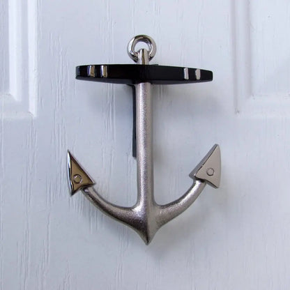 Metallic anchor-shaped door knocker on a white wooden door
